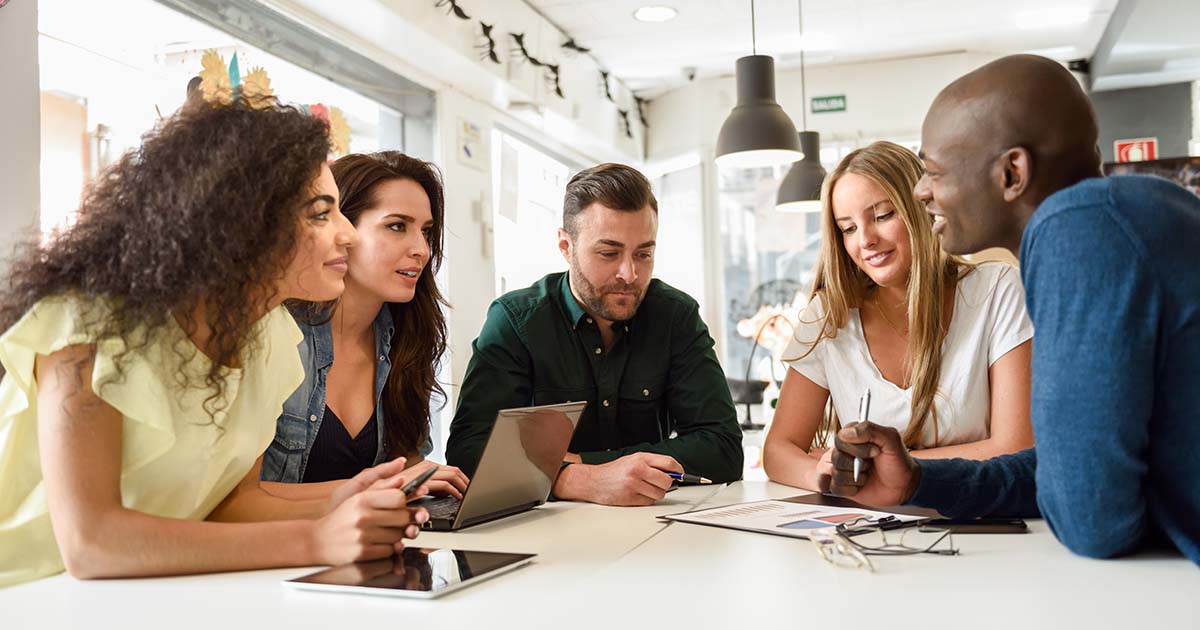 Multi-ethnic group of young people studying together on white de